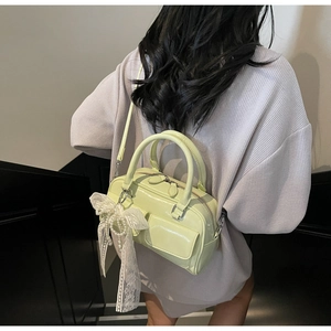 Détail d'un sac à main vert clair brillant avec un nœud en dentelle et des perles