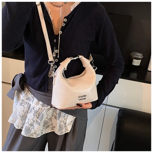 Detail of light beige glossy leather crossbody bag with silver metal handle and logo
