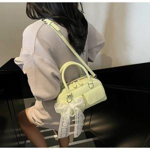 Détail du sac Boston vert clair avec poches frontales et nœud en dentelle et perles