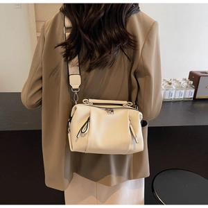 Chic beige litchi leather pillow bag with wide canvas strap shown in lifestyle setting