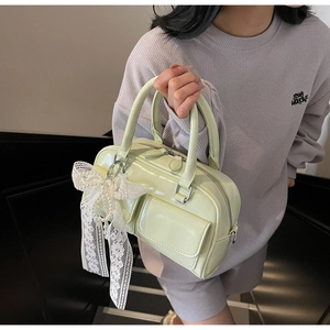 Detail of mint green patent leather bowling bag with lace bow and pearl pendant