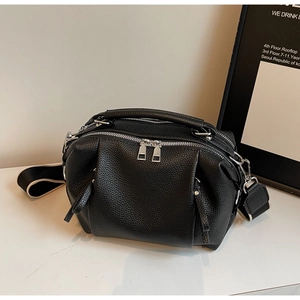 Close-up of black lychee grain leather crossbody bag with dual silver zippers and wide strap