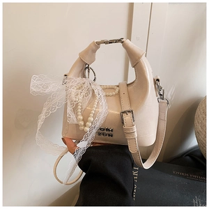Detail of cream white leather handbag with pearl chain and large white lace bow accent