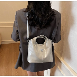 Detail of silver metallic leather handbag with triangular logo and adjustable strap