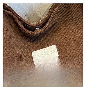 Close-up of coffee brown corduroy fabric with brand patch and detailed ribbed texture