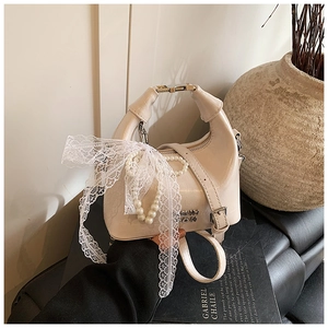 Detailed view of cream PU leather dumpling bag with lace ribbon and pearl charm