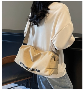Detail of khaki canvas crossbody bag with wide shoulder strap and side brand lettering