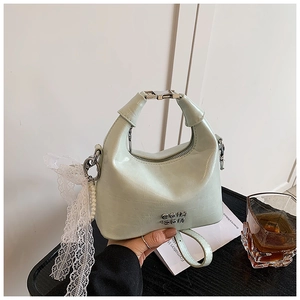 Macro shot of mint green pleated dumpling bag with pearl lace charm and gold hardware