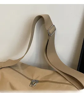 Detail of adjustable shoulder strap and metal zipper on khaki canvas hobo bag