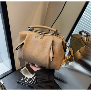 Detail of light brown lychee leather Boston bag with wide woven strap and silver zipper