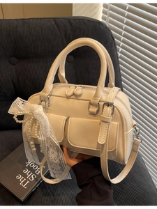 Sac bowling crème avec nœuds en dentelle et breloques perles sur canapé gris