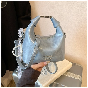 Detail of light blue metallic bag with knotted handle, pearl charm and metal logo