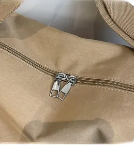Detail view of khaki canvas bag featuring smooth silver double zipper metal closure