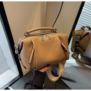 Detailed view of camel lychee leather pillow bag with dual zippers and wide strap