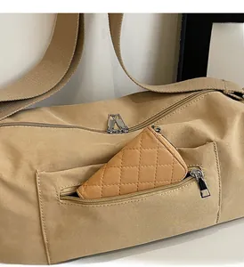Detail of khaki nylon bag showing front zipper pocket and quilted leather pouch insert