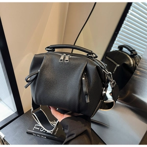 Detailed macro view of black lychee grain leather handbag with silver zippers and hardware