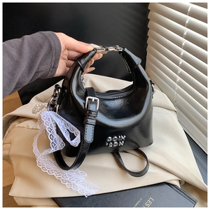 Macro detail of glossy black leather bag with silver metal letters and lace ribbon