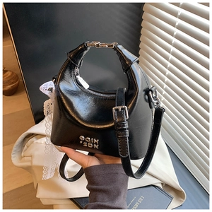 Detailed shot of black patent leather bag with silver metal handle and lace bow detail