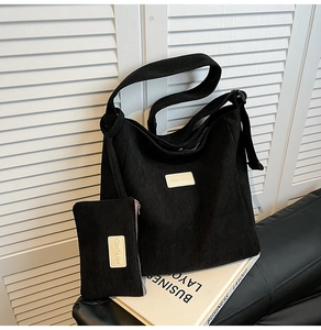 Detail of black corduroy hobo bag and matching coin purse set on aesthetic background