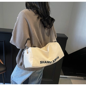 Rear view of model wearing a large off-white canvas pillow bag with black lettering