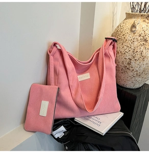 Detail view of pink corduroy tote bag and small zipper pouch with textured stripes