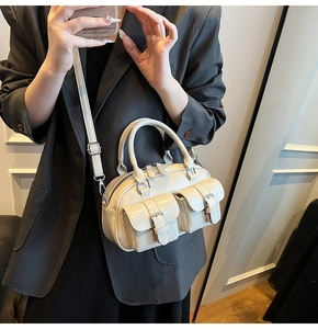 Vue détaillée du sac Boston crème avec deux poches à rabat et finition en cuir brillant