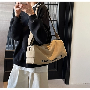 Detail of khaki canvas crossbody bag showing large capacity and soft cylinder shape