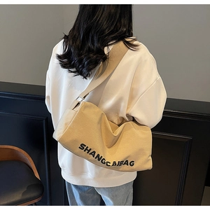 Detail of khaki canvas crossbody bag with large capacity and wide strap on model