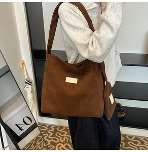 Detail view of large brown corduroy tote bag featuring leather label and small matching pouch