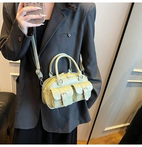 Détail d'un sac bowling vert clair avec deux poches avant et boucles métalliques argentées