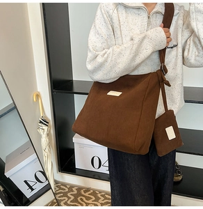 Detailed view of a brown corduroy tote bag with adjustable wide strap and mini pouch