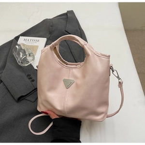 Detail view of pink leather shoulder bag with hollow handle and silver metal logo