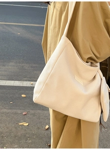 Detail of off-white corduroy tote bag with matching small zippered pouch in outdoor setting