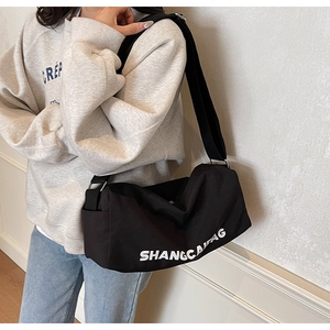 Detail of the black canvas crossbody bag with white SHANGCAI letters and adjustable strap