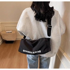 Detail of black canvas messenger bag featuring white bold SHANGCAIBAG lettering print