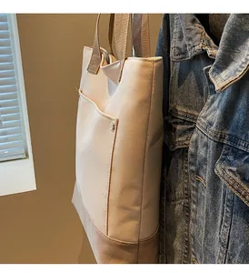 Detail of canvas bucket bag with metal logo button and large beige exterior pocket