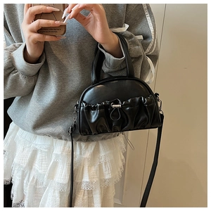 Detail of black pleated crossbody bag with silver buckle and elegant top handles