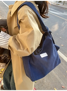 Detail of navy corduroy tote bag showing ribbed texture and minimalist white logo tag
