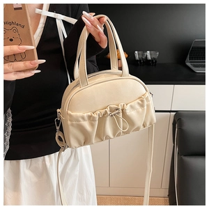 Close-up of cream PU leather handbag featuring pleated texture and metal drawstring details