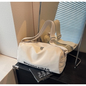 Detail view of the cream canvas pillow bag showing its cylindrical shape and metal zipper