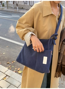 Detailed texture of dark blue corduroy tote bag featuring adjustable strap and front pocket