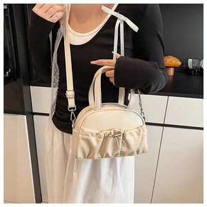 Detail of cream crossbody pillow bag with ruched pocket and adjustable shoulder strap