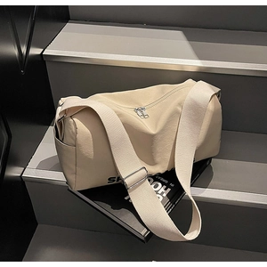 Detail of minimalist beige canvas crossbody bag with dual silver zippers and wide strap