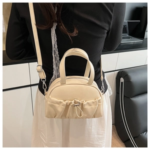 Back view of model wearing a cream ruched shell bag with drawstring detail and top handles