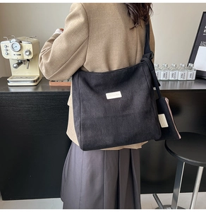 Detail view of black corduroy tote bag showing ribbed texture and matching mini zip pouch