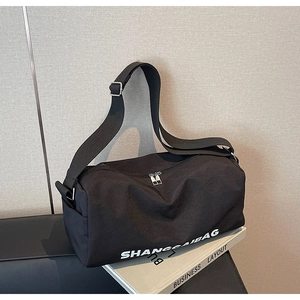 Detail view of black canvas pillow bag with white text logo and adjustable wide shoulder strap