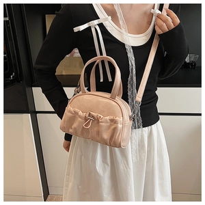 Detail of light pink pleated leather crossbody bag with metal ring and top handles