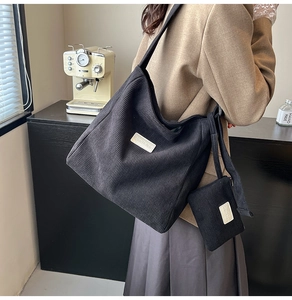 Detail of black corduroy tote bag with matching mini coin purse and brand logo