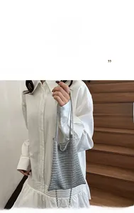 Detail of silver metallic woven tote bag with openwork mesh and thin chain strap decoration
