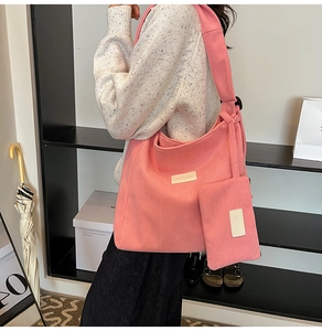 Detail shot of a large pink corduroy tote bag with matching pouch shown on a shoulder